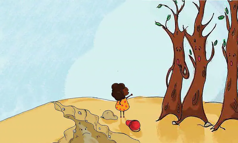 A girl stands near dried trees looking at a dry riverbed with her red bucket lying on the sandy ground.