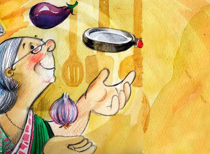 A grandmother with glasses in a green sari flips a pan with an eggplant while holding an onion in her kitchen with wooden utensils.