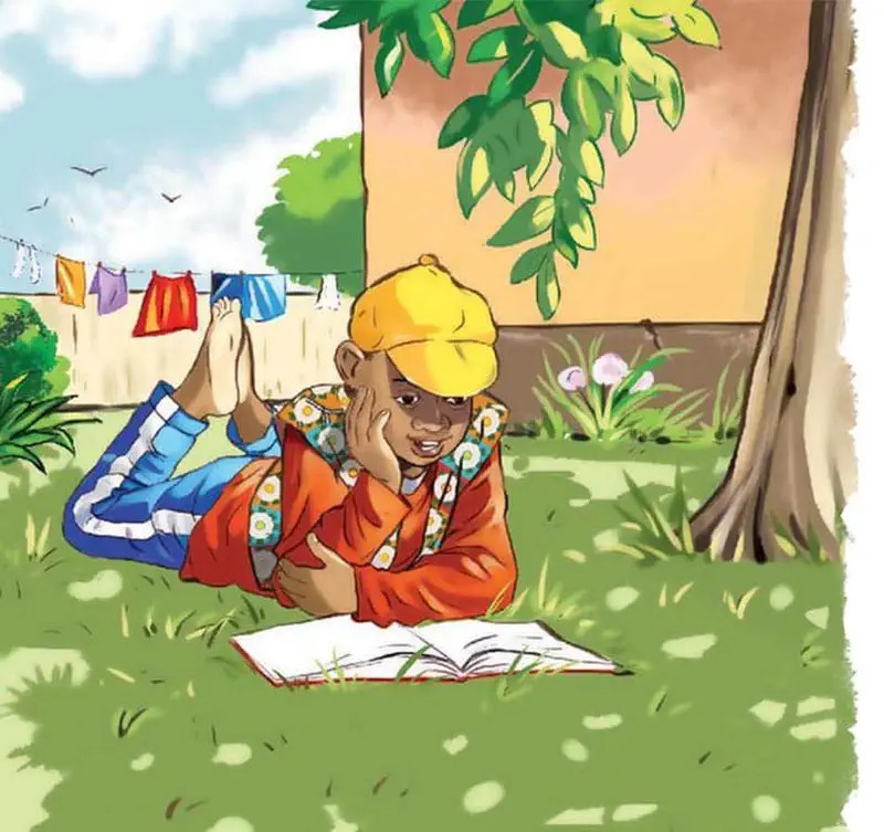 A boy named Kojo in a yellow cap and orange shirt lies on grass reading a book, with laundry on a clothesline behind him.