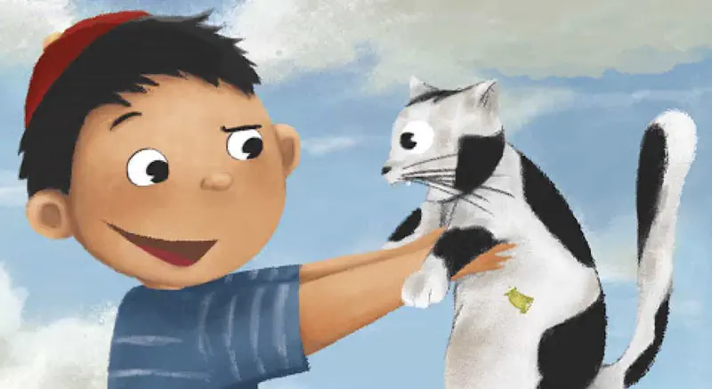 Happy boy petting black and white cat against blue sky background.