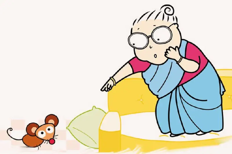 Grandmother in blue sari pointing at scared mouse near yellow couch with green pillow.