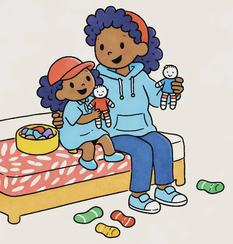 On the left side of the image, Mom and Alana sit together on a bed with a patterned red-and-white bedspread. Mom holds up a small completed sock doll, smiling contentedly, while Alana sits on her lap holding another finished sock doll, looking happy and engaged. Between them on the bed is a bowl filled with colorful materials for crafting. Several loose socks in various colors (green, yellow, red-striped) are scattered on the floor to the right of the bed. The scene is set indoors in a bright, cheerful bedroom.