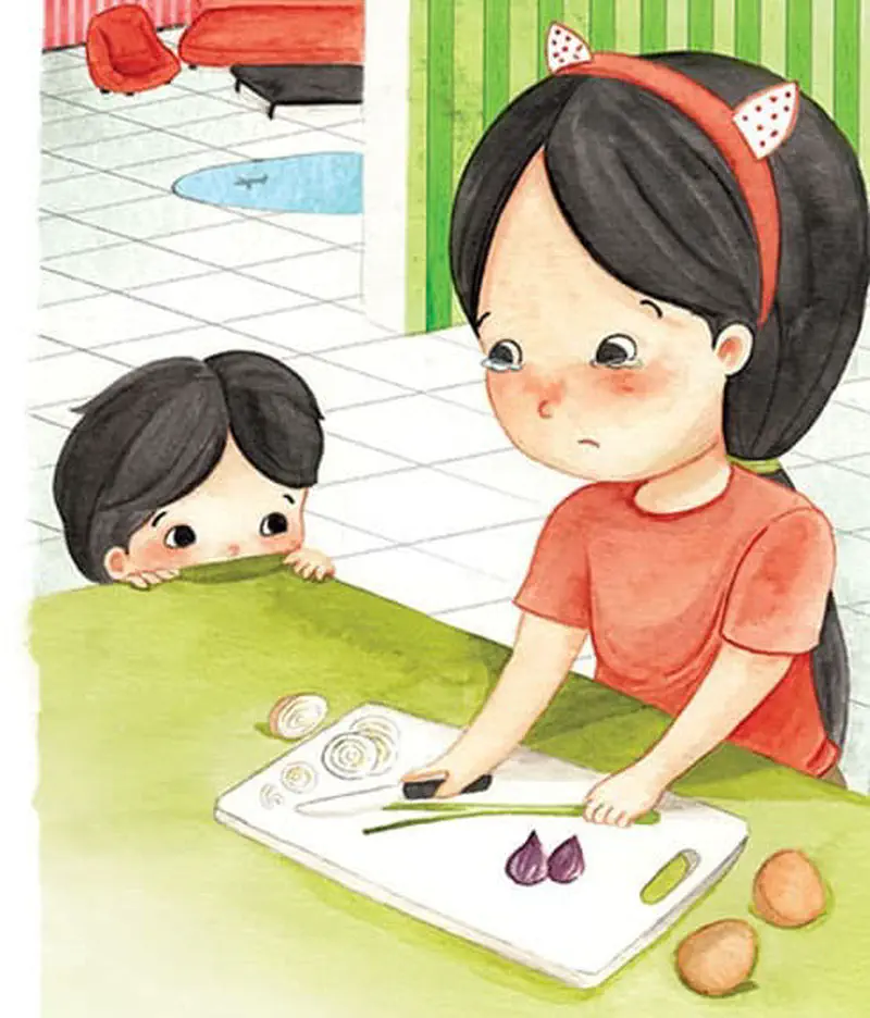 A girl with tears in her eyes cuts onions at a green kitchen counter while a little boy peeks over the edge watching her curiously.