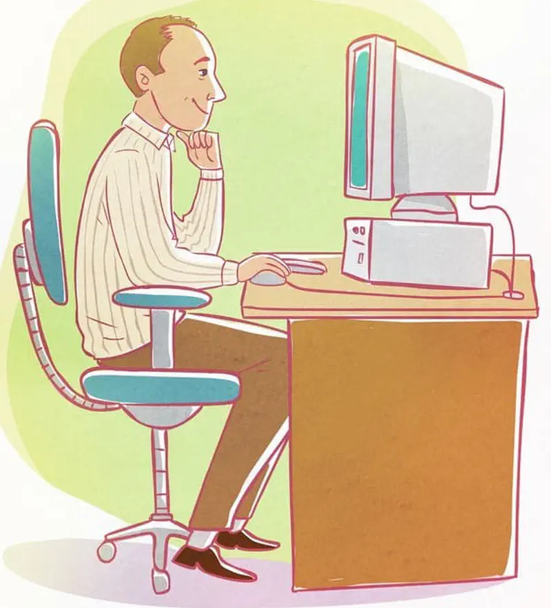 A man in a striped shirt sits at a desk using a desktop computer with monitor, tower, and printer.