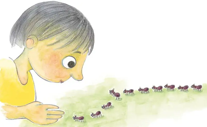 A curious child in yellow lies on the grass watching a line of ants march past, face close to the ground in wonder.