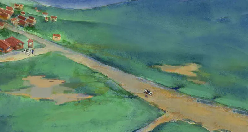 Aerial view of a rural village with red-roofed houses, a child and cow walking on a winding dirt road through lush green countryside.