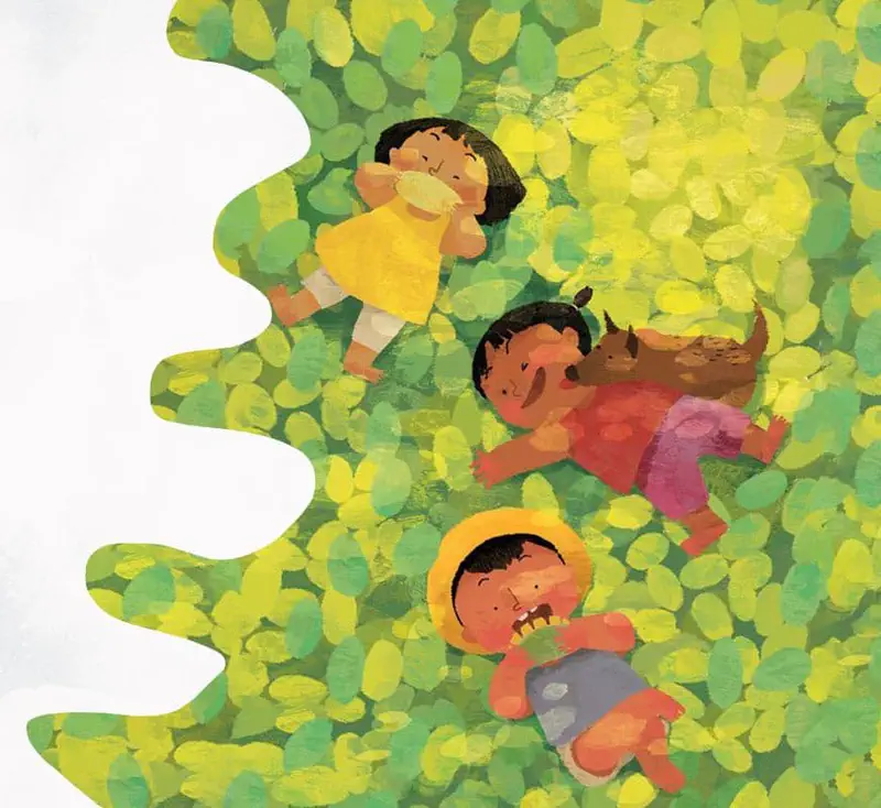 Three children and a dog lie happily on a bed of green leaves. One eats a mango, another cuddles the dog, and a boy in an orange hat smiles.