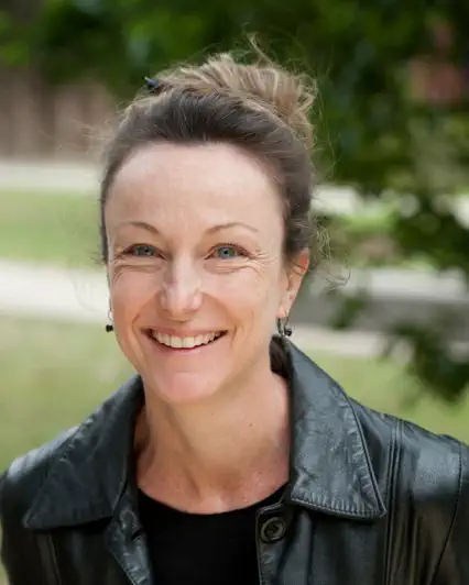 Professor Genevieve McArthur smiling outdoors, wearing a black leather jacket