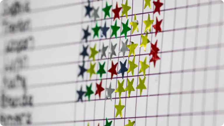 a close up photo of a star chart with gold, blue, res and silver stars stuck to it.