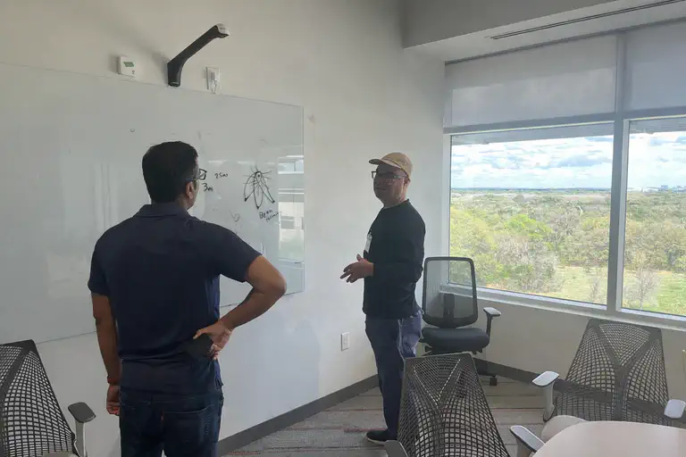 Vikash Kumar and Adrian DeWitts discussing technical approaches at a whiteboard during the Arm workshop